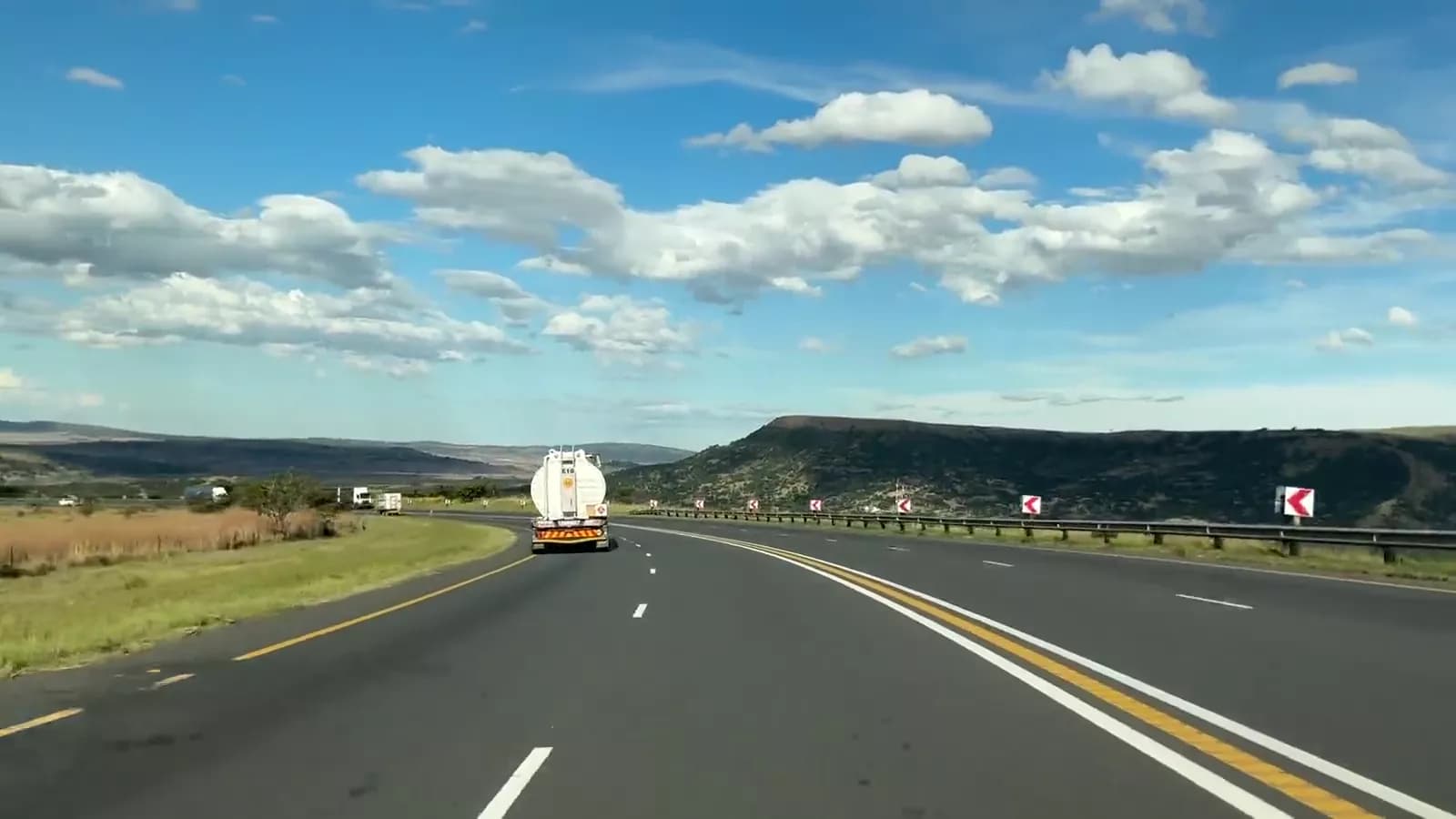 A freight corridor at speed: a fuel tanker and a curtain-sider on an open highway.