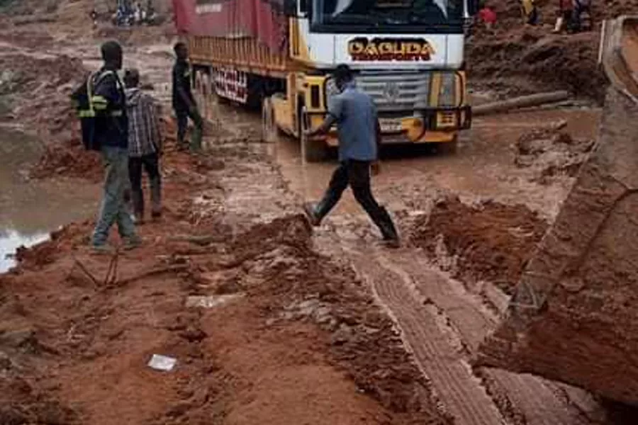 A Daouda Transport truck working through deep laterite mud on a forest road.